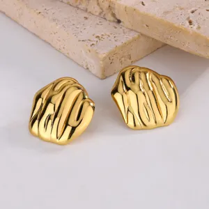 Détail de boucles d'oreilles cœur dorées style français avec texture ondulée unique.