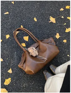 Vista dettagliata di una grande borsa tote retrò in pelle marrone su foglie di ginkgo