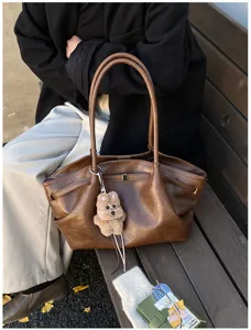 Foto lifestyle di una borsa tote retrò in pelle marrone con ciondolo a orsetto