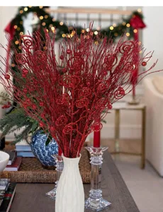Rote glitzernde Weihnachtszweige mit Spiralen und Beeren in einer eleganten weißen Vase.