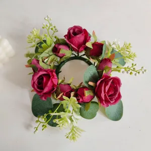 Detalle de rosas rojas artificiales y vegetación en una corona de velas floral