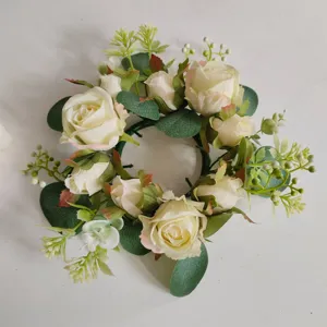 Detalle de una corona para velas con rosas blancas artificiales y hojas de eucalipto.