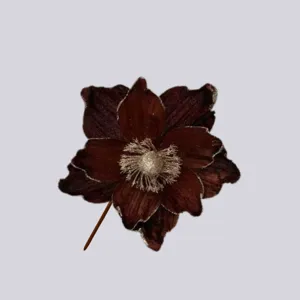 Primo piano dettagliato di un fiore di Natale artificiale marrone scuro con bordi dorati.