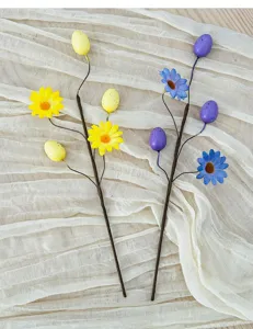 Close-up of artificial daisy stems and spotted Easter eggs arranged on textured fabric