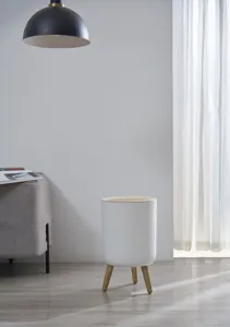 Modern Japanese style white round trash can with wooden legs in minimalist home setting