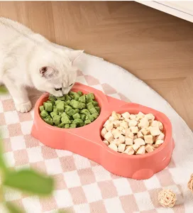 Weiße Katze frisst aus einem korallenroten Doppelnapf mit gefriergetrocknetem Futter.