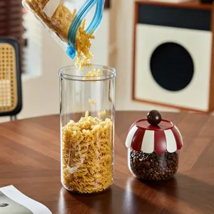 Large clear kitchen storage canisters for pasta and coffee beans on a wooden table