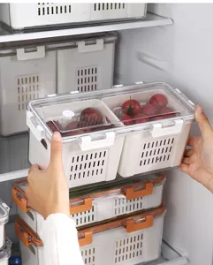 Detail of a hand holding a transparent refrigerator food storage box with drainage.