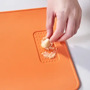 Durable orange food-grade TPU cutting board with built-in garlic grater feature.