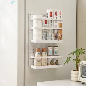 White wall-mounted kitchen pegboard rack for refrigerator side storage.