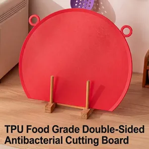 Vibrant red TPU food-grade double-sided antibacterial cutting board on a wooden stand.