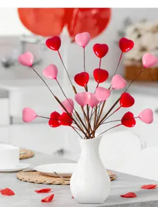 Picchi decorativi a cuore rossi e rosa in vaso bianco per l'atmosfera di San Valentino.