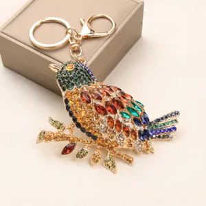 Detailed view of a vintage rhinestone-encrusted magpie bird keychain on a gold alloy base