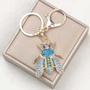 Nahaufnahme eines funkelnden bunten Strass-Bienen-Schlüsselanhängers auf einer Geschenkbox