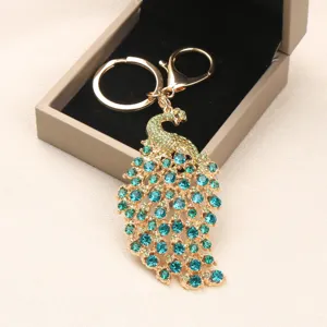 Vintage gouden pauw sleutelhanger met blauwe en groene strass steentjes in geschenkdoos