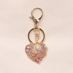 Close-up of heart-shaped keychain with pearls and crystals on beige background