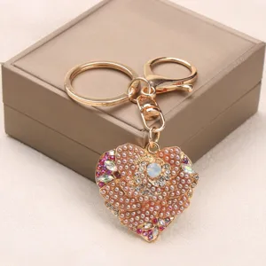 Rose gold heart-shaped keychain with floral rhinestone details on a jewelry box background