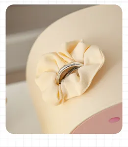 Close-up of a cream hair scrunchie with silver ring on a desktop cosmetic organizer