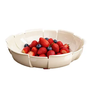Eleganter cremefarbener Obstteller in Blütenform mit frischen Erdbeeren und Blaubeeren