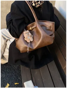 Dettaglio di una borsa tote grande vintage in ecopelle marrone con charm orsetto.