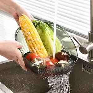 Transparent green kitchen colander washing corn and lettuce under running water in sink