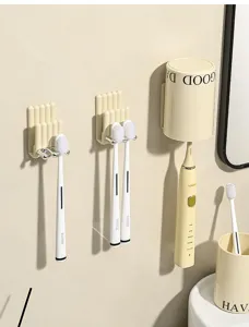 Dettaglio del supporto a parete color crema per spazzolino elettrico e bicchiere