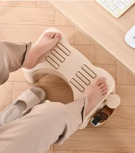 Person using an ergonomic office footrest with massage rollers at a wooden desk