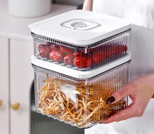 Détail de boîtes de rangement sous vide tenues à la main, texture côtelée visible.