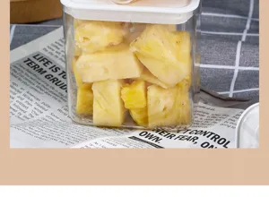Detail shot of a transparent plastic container filled with fresh pineapple chunks.