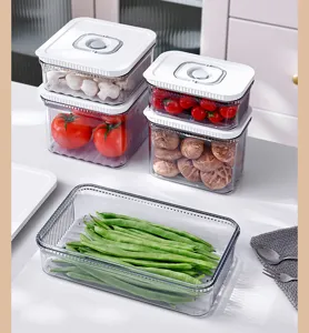 Détail des boîtes de conservation sous vide transparentes avec des légumes frais.
