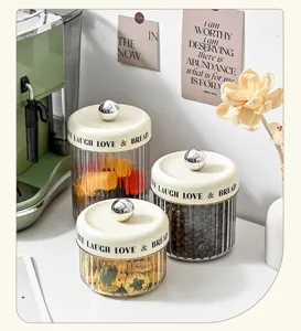 Three luxury fluted clear jars with cream lids and silver knobs in a kitchen setting.