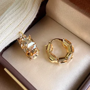 Primo piano di eleganti orecchini a cerchio color champagne con strass quadrati scintillanti.