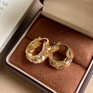 Primo piano di orecchini a cerchio quadrati con strass color oro champagne in box.