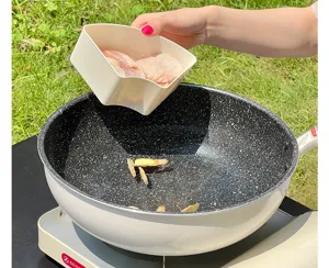 Close-up of a white kitchen storage container with handle pouring meat into a wok.