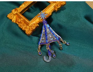 Detailansicht einer blauen Vintage-Regenschirmbrosche mit Schneeflocken und Quasten