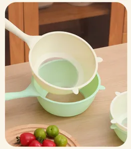Detailed view of cream and light green kitchen colanders with fine mesh and long handles