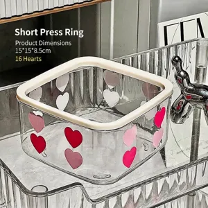 Close-up detail of a clear desktop storage box with cute pink heart patterns and rim.