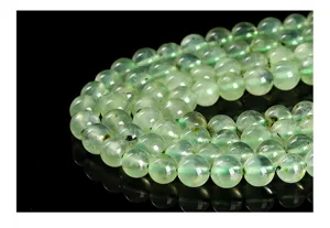 Vue macro de perles rondes en préhnite naturelle vert clair sur fond noir réfléchissant