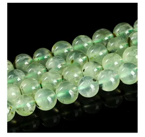 Détail macro de perles rondes en préhnite naturelle montrant une texture verte claire