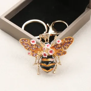 Exklusiver goldener Bienen Schlüsselanhänger mit lila Strasssteinen und rosa Blumen