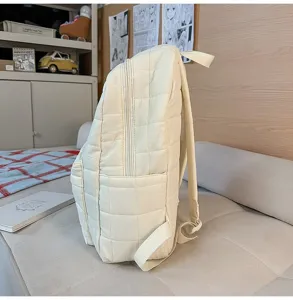 Gedetailleerd zijaanzicht van een crème gewatteerde rugzak in een minimalistische binnenruimte