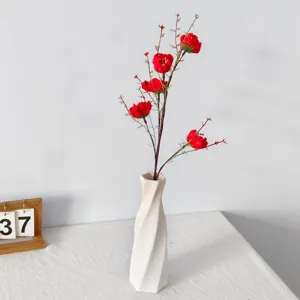 Flores artificiales rojas vibrantes en un jarrón blanco retorcido para todo el hogar