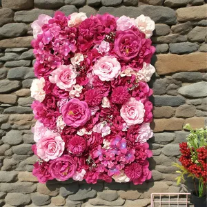 Vista detallada de una pared de flores artificiales fucsia y rosa sobre piedra