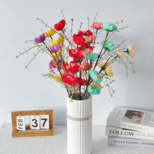 Vista detallada de flores artificiales coloridas en un jarrón blanco con accesorios hogar