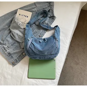 Large denim dumpling bag with green tablet for size reference in a casual setting
