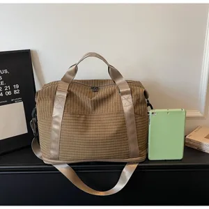 Large capacity brown checkered travel bag shown next to a green tablet for size reference