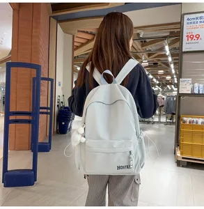 Rückansicht einer Person mit einem hellblauen, großvolumigen Schulrucksack mit Plüschanhänger