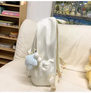 Seitenansicht eines cremefarbenen Rucksacks mit Plüschsternanhänger und Seitentasche