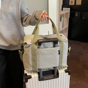 Gran bolsa de viaje a cuadros para mujer con correa para maleta y asas verdes.