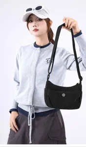 Detailed shot of a stylish black nylon crossbody bag carried by a model